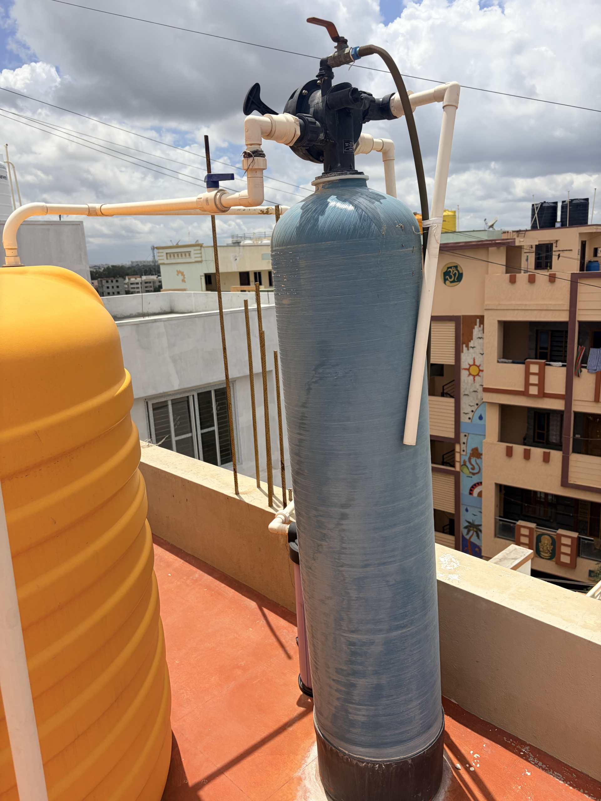 Water softener resin tank and control valve installed on a rooftop plumbing line